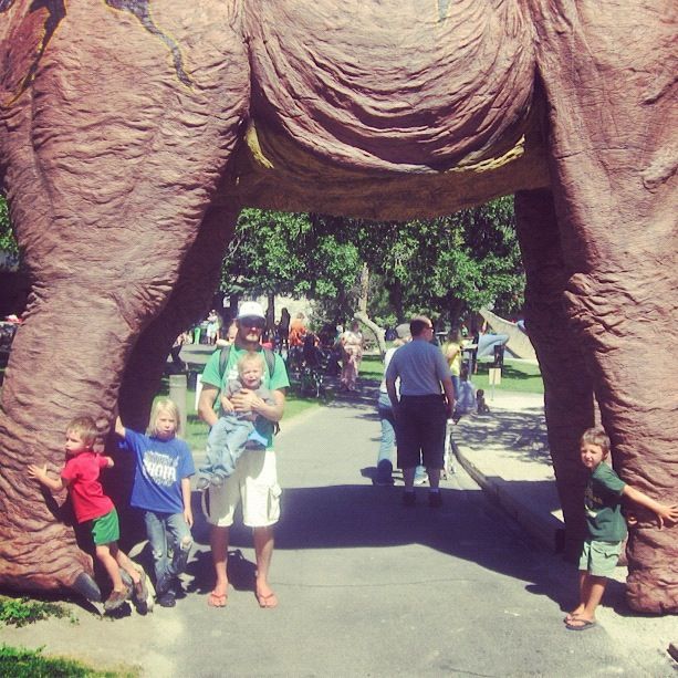 family standing under giant dinosaur brontosaurus instagram