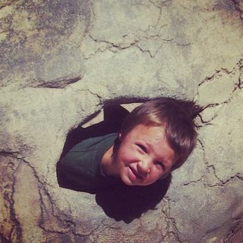 little boy dinosaur playground looking out of hole instagram